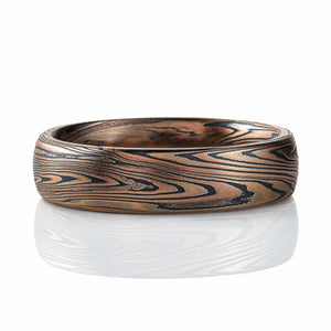 overall coppery brown color looking ring, made with red and yellow gold and oxidized silver (black). The ring is domed and patterned in a twisting, zigzagging style.