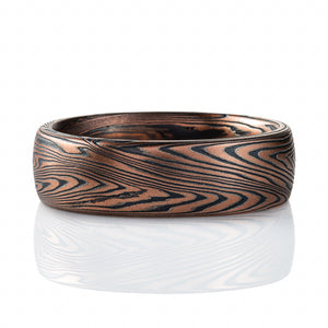 Domed mokume gane band made with linear style patttern, long lines swooping and curling, made with layers of gold and silver.