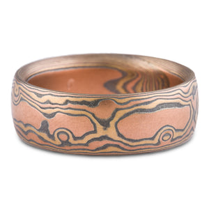 Mens wedding band made with mokume gane, a technique used to create a wood grain look with layers of different colored metal. This ring is made with red gold, oxidized silver and yellow gold. 