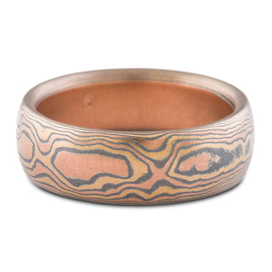 Rustic feeling mens wedding band made with mokume gane, layers of red gold, silver and yellow gold, resembling a warm toned wood grain.